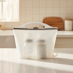 A translucent white baby bottle caddy with a handle and side loop, holding two baby bottles, set on a kitchen countertop with a tiled backsplash in the background.